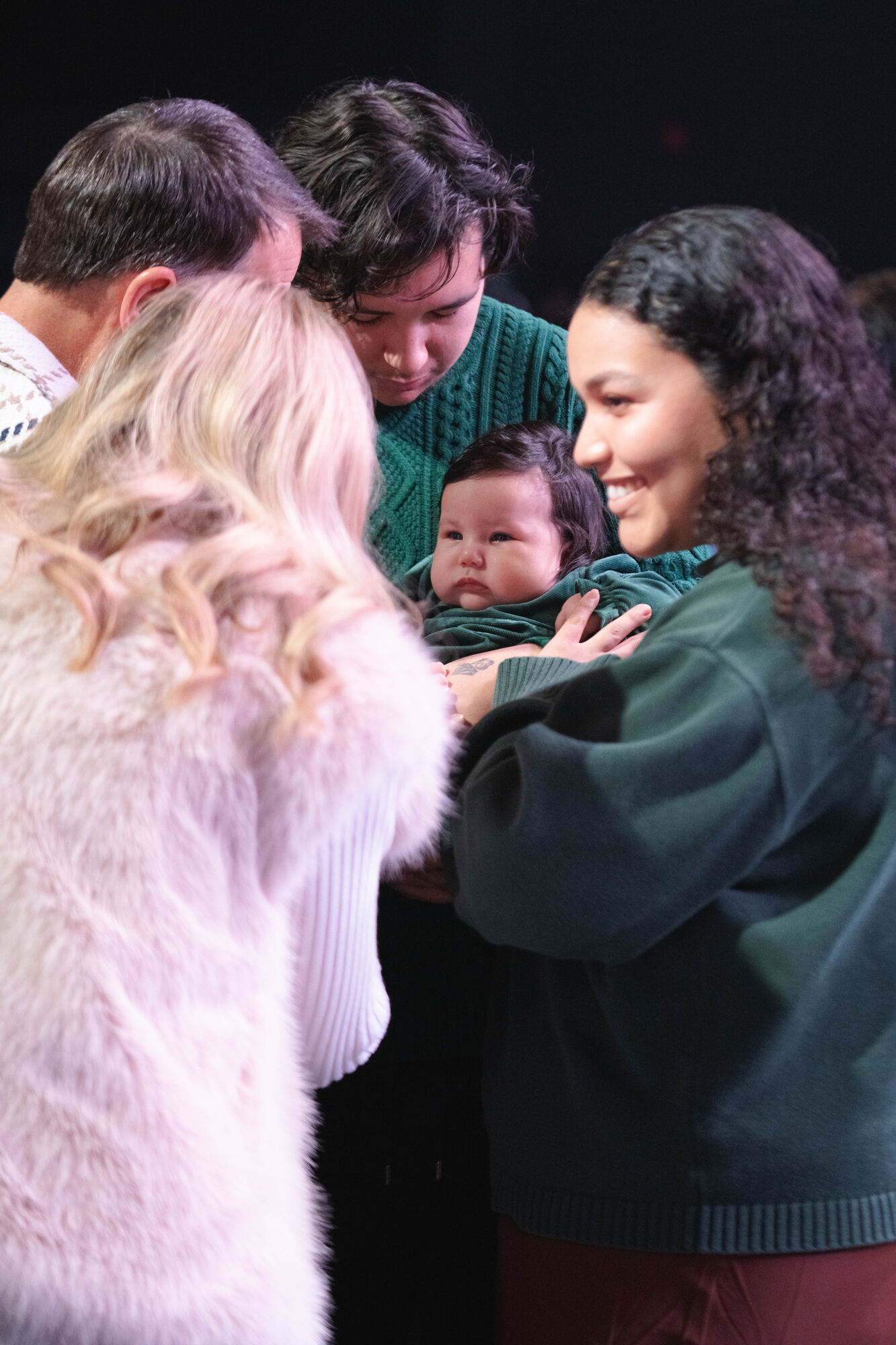 Parents praying with their child at the front of the room