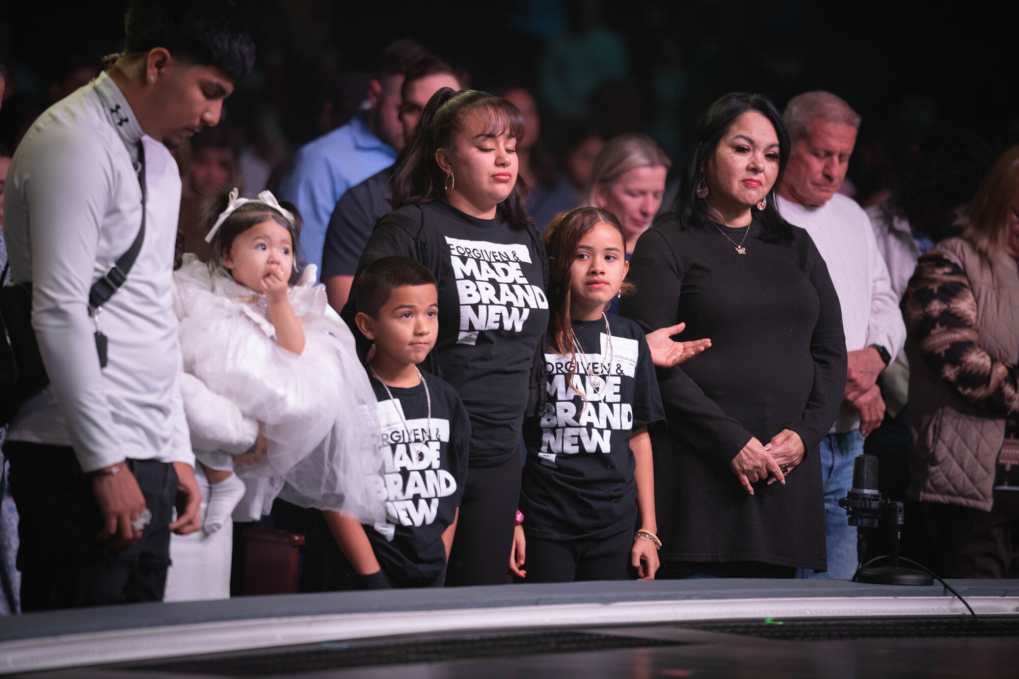 Three generations of one family standing together at the front during a dedication service