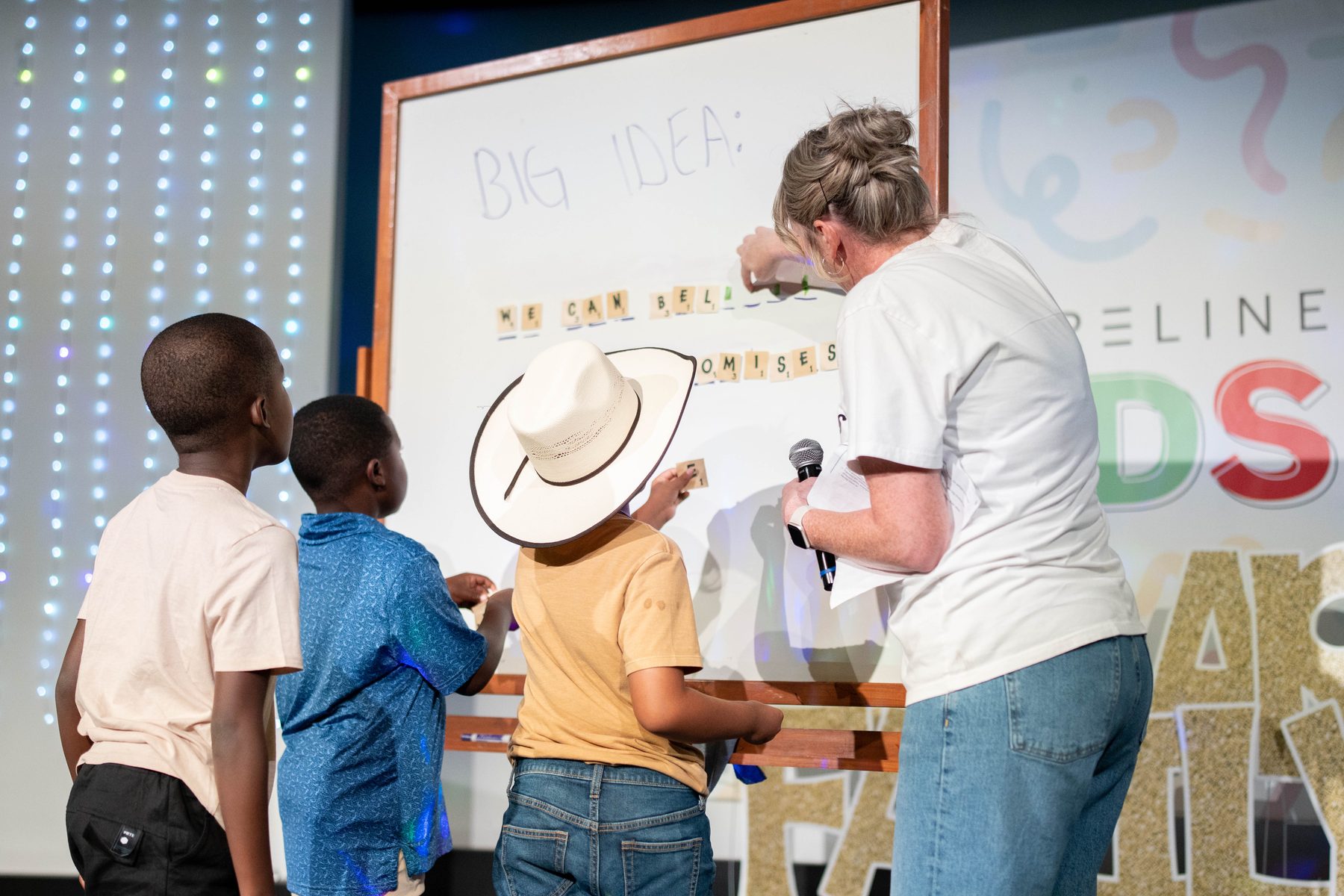 Kids at the whiteboard on the ShorelineKids stage, spelling out the Big Idea with a leader
