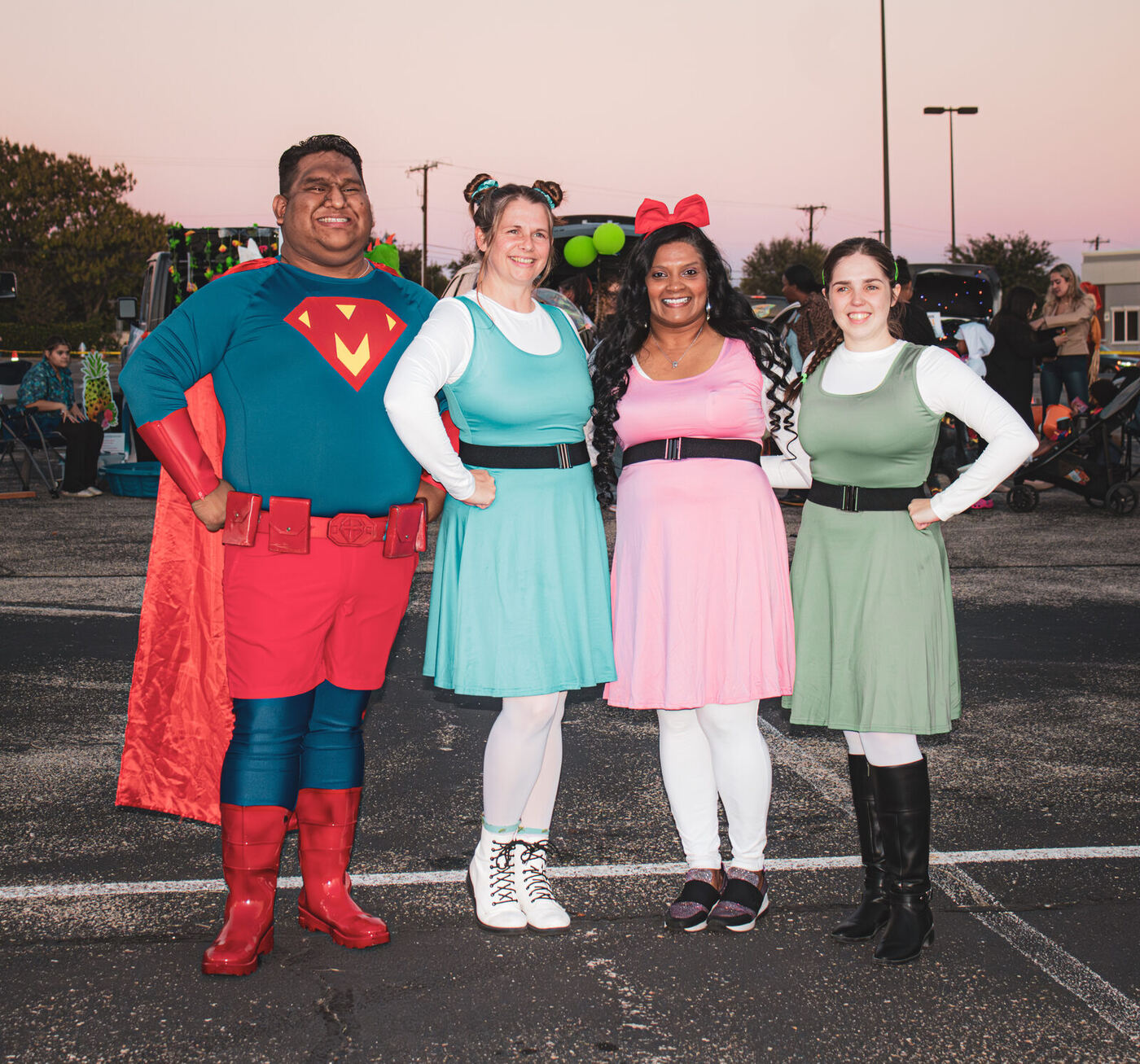 Four adults in matching superhero costumes at sunset