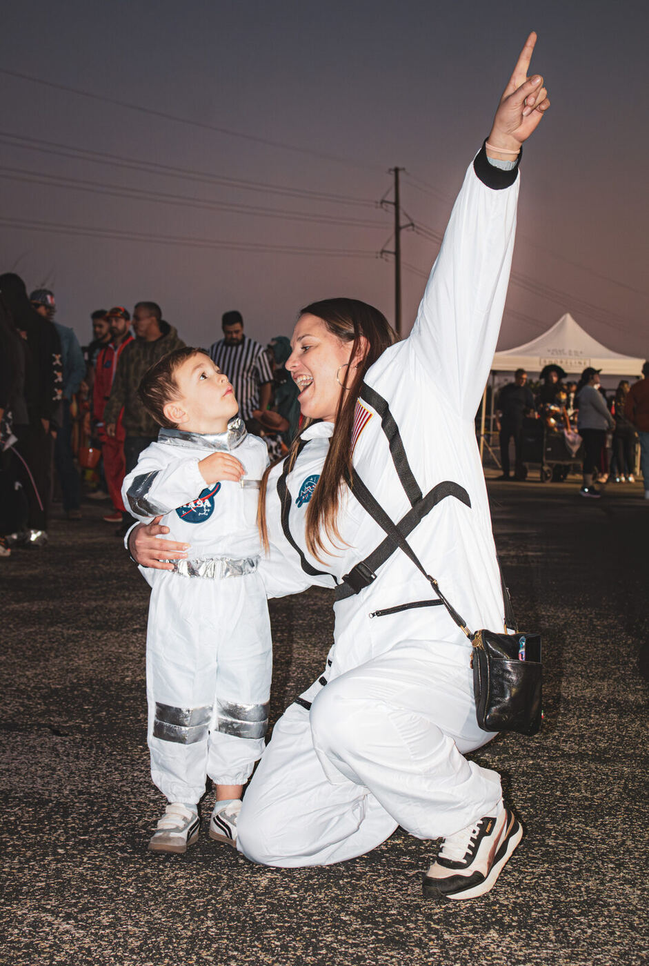A mum and her son in astronaut suits pointing at the sky