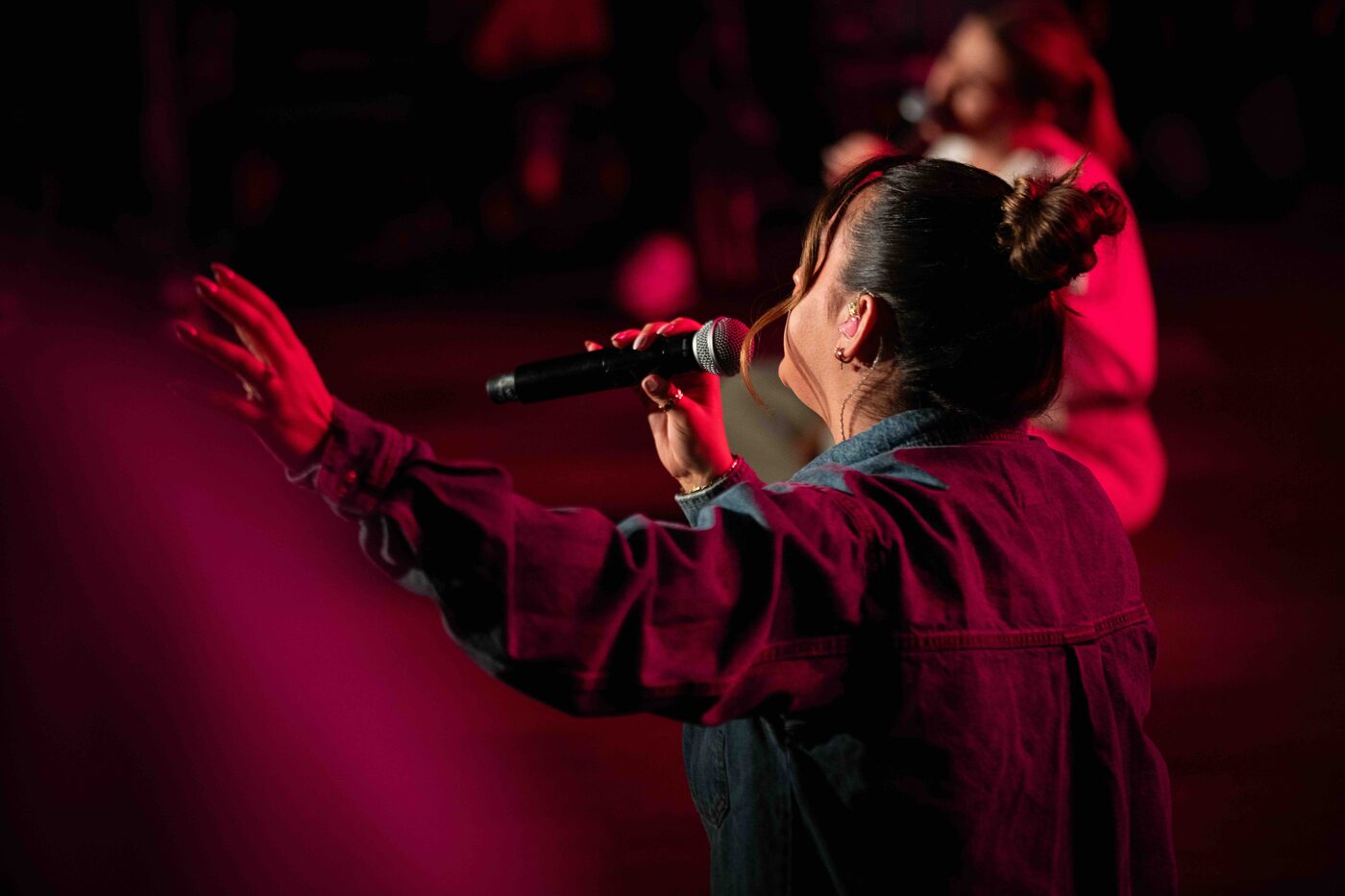 A worship leader singing with a hand raised at Shoreline Young Adults